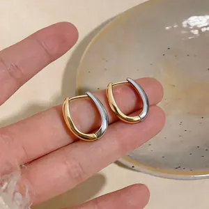 Dettaglio di orecchini a cerchio vintage bicolore oro e argento tenuti in mano