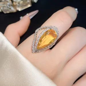 Detailed view of large teardrop yellow zircon ring with micro-pave halo on finger
