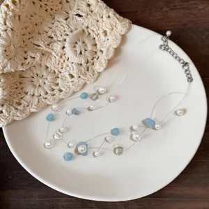 Vista dettagliata di una collana multistrato minimalista con pietre blu e perle.