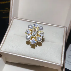 Detailed macro shot of vintage flower ring with pearls and zircons in a beige jewelry box