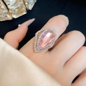 Close-up detail shot of an elegant pink pear-shaped zircon halo ring on a finger