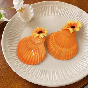 Gros plan de barrettes en forme de coquillage orange avec fleurs en tissu sur une assiette