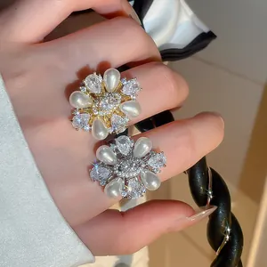 Close-up of elegant flower-shaped rings with teardrop pearls and sparkling zircons