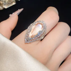 Close-up of elegant pear-shaped zircon ring on hand, featuring halo stones and adjustable band.