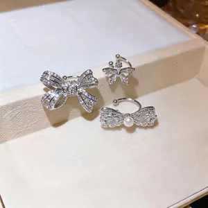 Elegant silver zircon ear cuffs with bow and flower designs, featuring a central pearl.