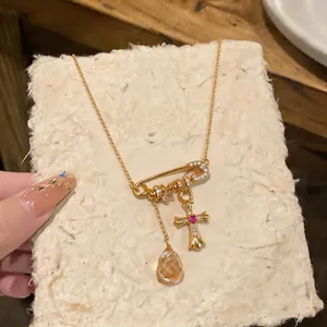 18k gold plated safety pin pendant necklace featuring a zircon cross and amber drop charm