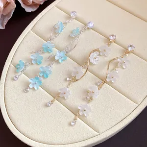 Close-up of elegant long tassel earrings with blue and white floral charms on jewelry tray