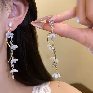 Close-up of elegant long tassel earrings with sparkling zircons and frosted flower petals.