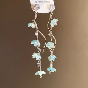 Detail of elegant long tassel earrings with blue flowers and sparkling zircons.