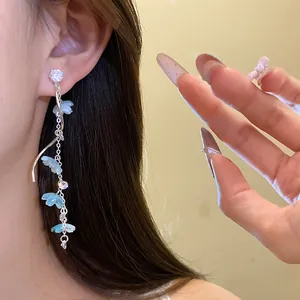 Close-up of elegant silver tassel earrings with light blue zircon flowers worn on model ear
