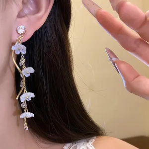 Close-up of elegant long tassel earrings with white flowers and sparkling zircons