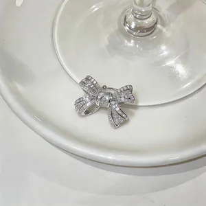Detailed view of a sparkling silver zircon-studded bow ear cuff on a white ceramic base.