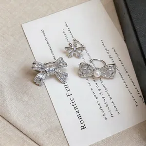 Detailed close-up view of elegant zircon butterfly and bow-shaped ear cuffs on a card.