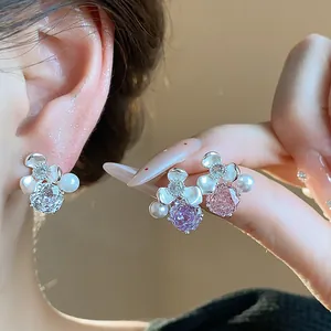Close-up detail of elegant floral zircon and pearl stud earrings with silver needles for women