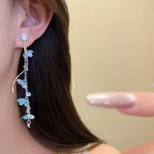 Close-up of elegant long tassel earrings with blue flowers and sparkling zircons.