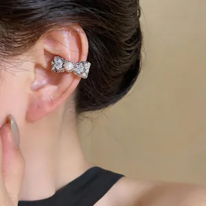 Detailed view of elegant zircon flower bow ear cuff with pearl detail worn on human ear