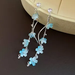 Detail view of long tassel earrings featuring blue resin flowers and zircon studs