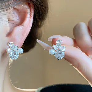 Close-up of elegant silver flower stud earrings with shimmering zircons and pearls.
