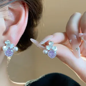 Close-up of elegant flower stud earrings featuring purple zircon and delicate white pearls.