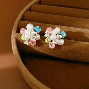 Close-up of elegant colorful flower cluster stud earrings with pearls and sparkling crystals