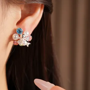 Close-up detail of colorful flower cluster pearl stud earrings with zircon stones worn on ear