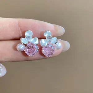 Detailed macro shot of elegant pink zircon flower and white pearl stud earrings