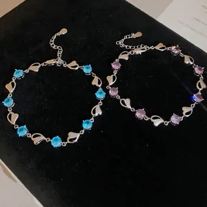 Elegant heart-shaped crystal bracelets in blue and purple styles on black velvet background