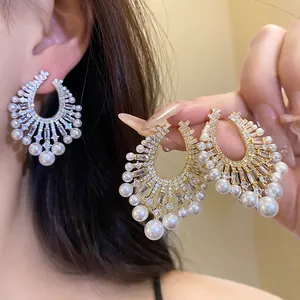 Detailed view of French vintage zircon pearl pendant earrings worn on ear and hand