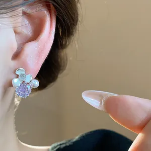 Detail shot of a delicate silver flower stud earring with purple zircon and pearls