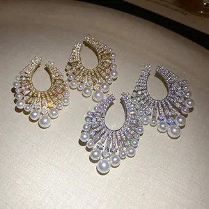Macro view of luxury zircon and pearl stud earrings in gold and silver tones style.