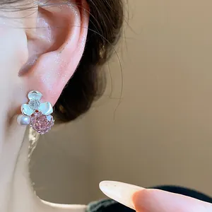 Close-up of elegant flower pearl stud earrings with pink zircon on model's ear