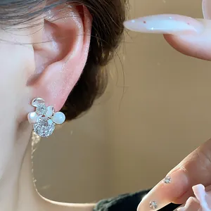Close-up detail of a delicate silver flower stud earring featuring pearls and zirconia stones