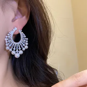 Detailed view of ornate silver hoop earrings featuring zircons and pearl accents