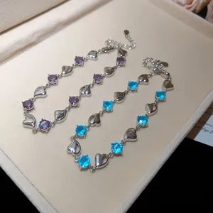 Close-up detail of silver heart shaped bracelets with vibrant purple and blue crystals