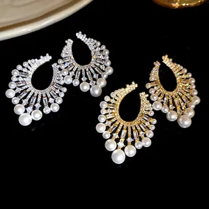 Detailed macro shot of vintage-style pearl and zircon U-shaped dangle earrings.