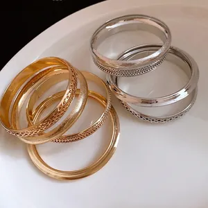 Set di bracciali rigidi metallici retrò con finiture testurizzate e lucide oro e argento