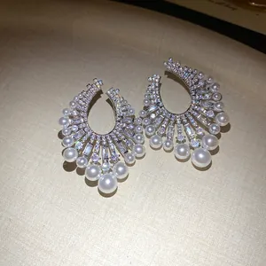 Macro detail of fan-shaped earrings with sparkling cubic zirconia and elegant white pearls