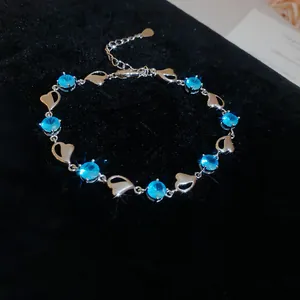 Close-up of silver heart bracelet with blue crystals on black velvet background