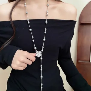 Long elegant pearl bead necklace featuring a sparkling diamond flower pendant on a model