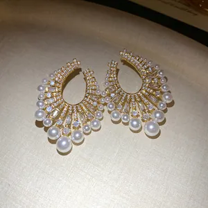 Close-up detail of vintage gold-tone earrings with pearls and shimmering zircons.