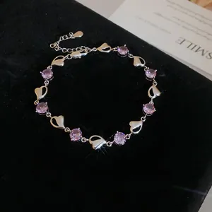 Close-up of elegant silver heart bracelet with purple crystals on black velvet background