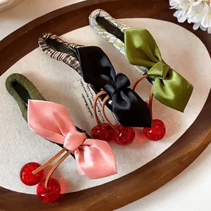 Elegant cloth bow hair clips with resin cherry charms in three colors on wood tray