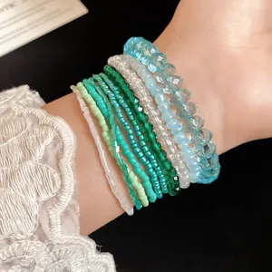 Detailed macro view of 10-piece bohemian beaded bracelet set in gradient blue and green.