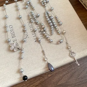 Close-up detail of elegant pearl beaded necklace featuring crystal flower and key charms