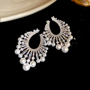 Detail view of ornate silver needle earrings with shimmering zircons and elegant pearls.