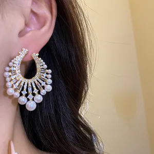 Close-up of vintage palace style gold earrings with pearls and sparkly cubic zirconia