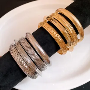 Vista dettagliata di bracciali metallici vintage con finiture testurizzate oro e argento.