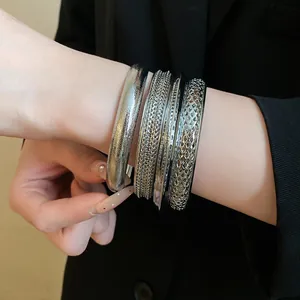 Primo piano di bracciali rigidi in metallo argentato vintage sul polso di una donna in abito