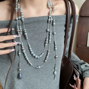 Close-up detail of silver-toned multi-strand necklace with gray pearls and charms