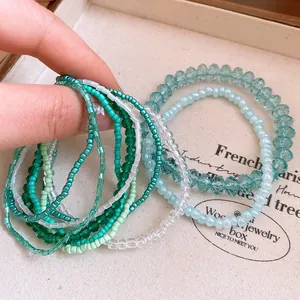 Close-up of a 10-piece green and teal acrylic beaded bracelet set with crystal accents